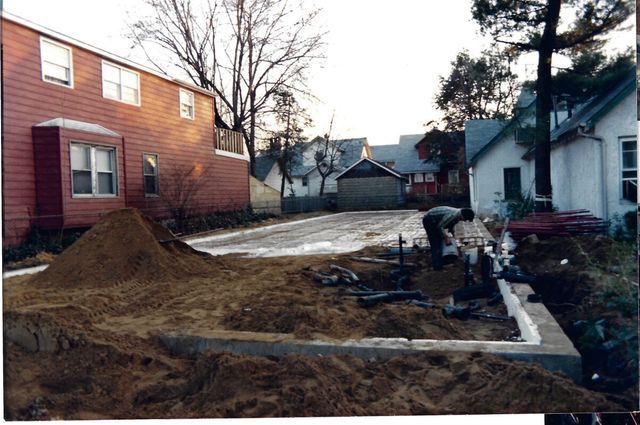 A man is digging in the dirt in front of a house