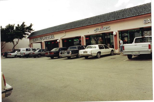 A row of cars are parked in front of a building that says glass