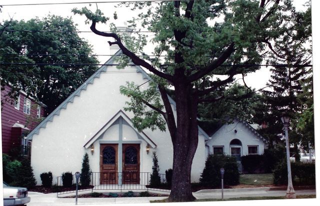 A white building with a tree in front of it