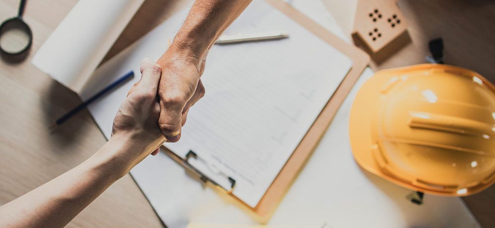 A man and a woman are shaking hands over a table.