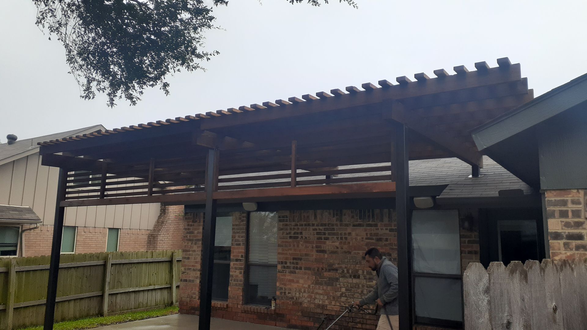 Partially constructed brick house with a corrugated metal roof and a person standing near the doorway.