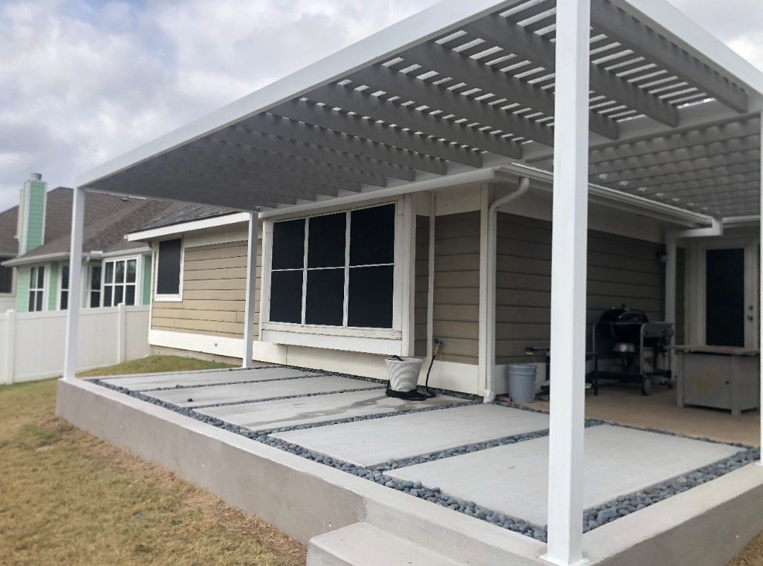 Covered patio with white pergola, gray decking, and sliding glass doors on a house