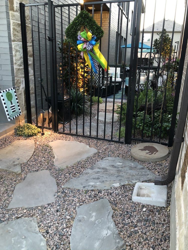 Black metal gate with festive wreath and bow over a stone-and-gravel front path