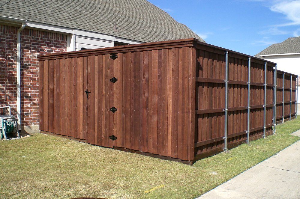 Brown wooden storage shed beside a brick house on a grassy backyard patio