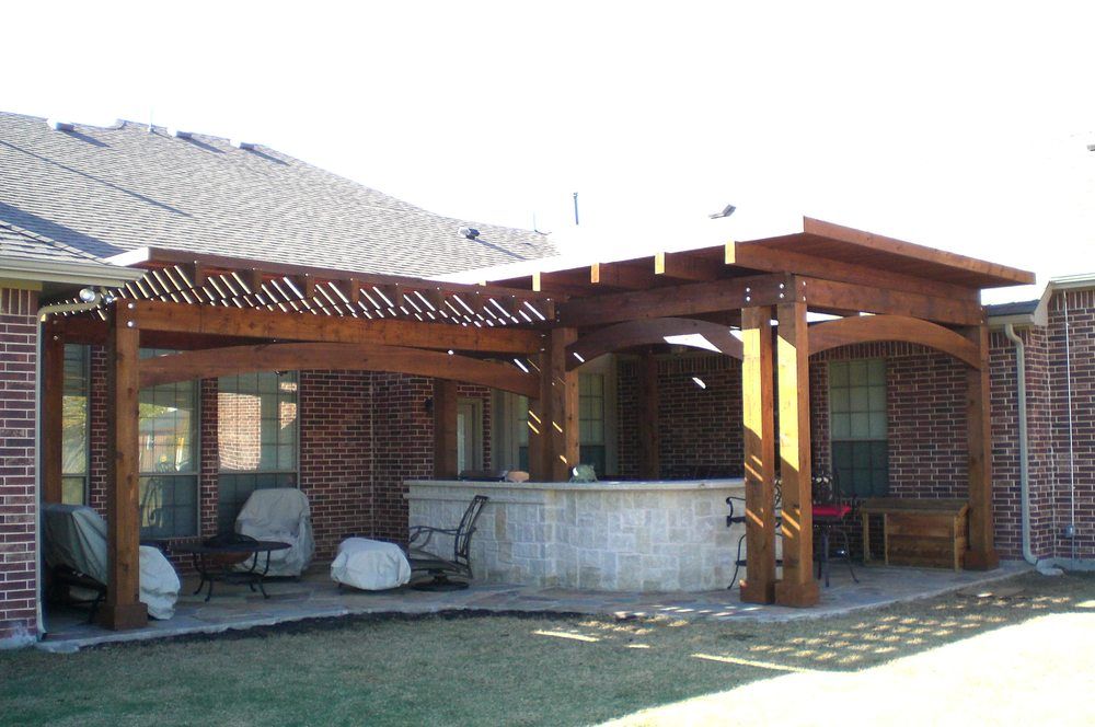 Backyard patio with wooden pergola, brick columns, and a concrete seating area