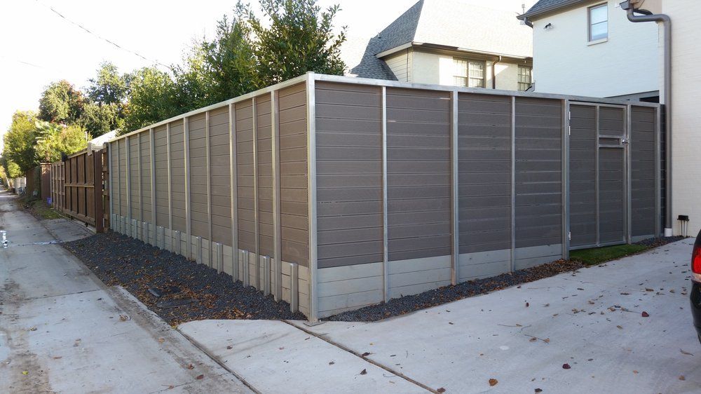 Corner lot with tall brown privacy fence and gray posts beside a sidewalk and residential street