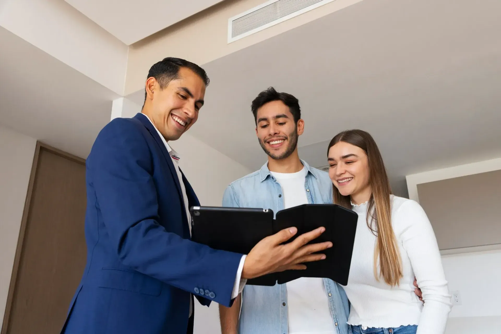 Three people smiling and looking at a folder in a bright office