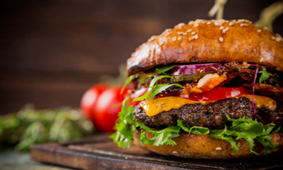 Close-up of a juicy cheeseburger with lettuce, tomato, onion, and melted cheese on a bun