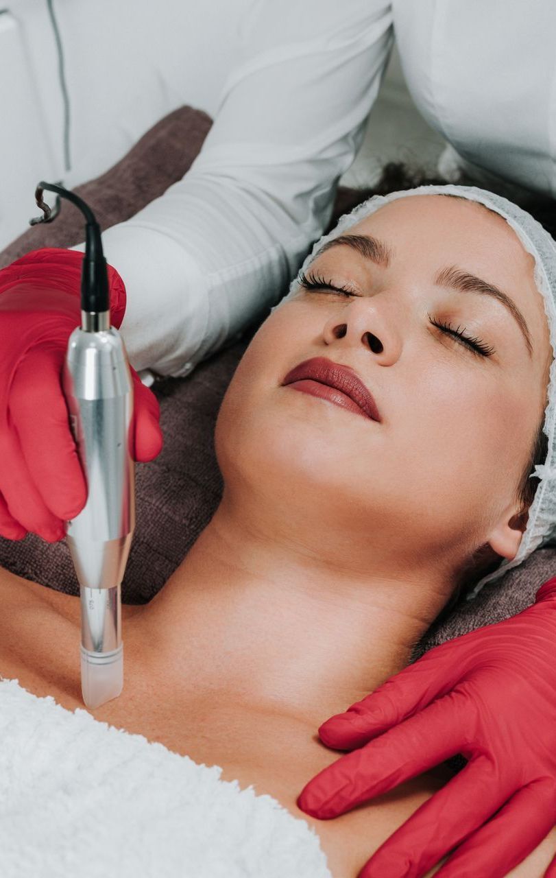 A woman is getting a facial treatment with a machine.