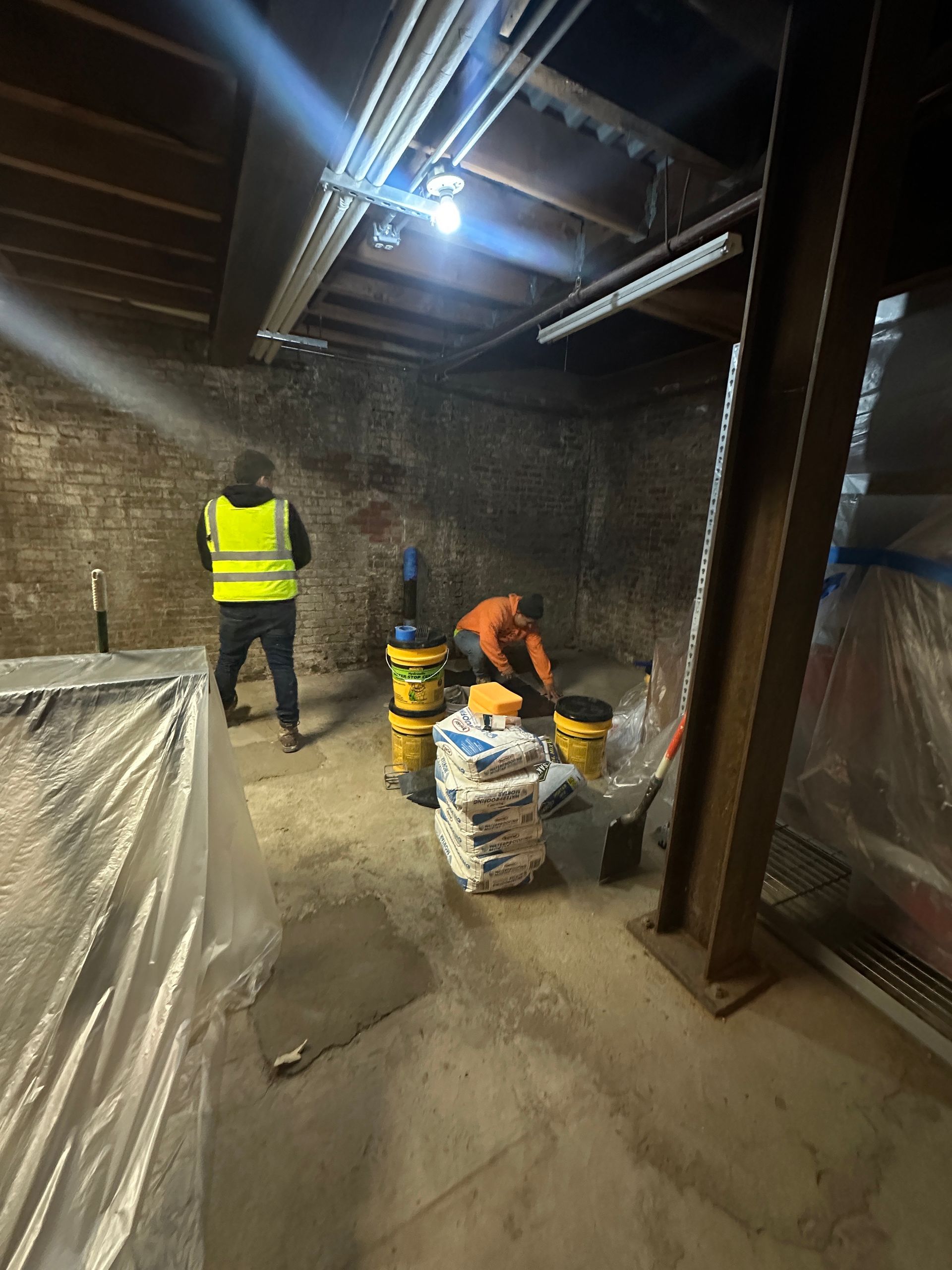 A group of construction workers are working in a basement.