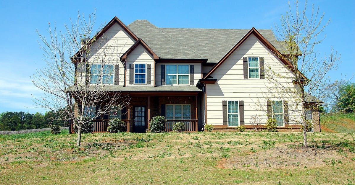A large house with a lot of windows is sitting on top of a grassy hill.