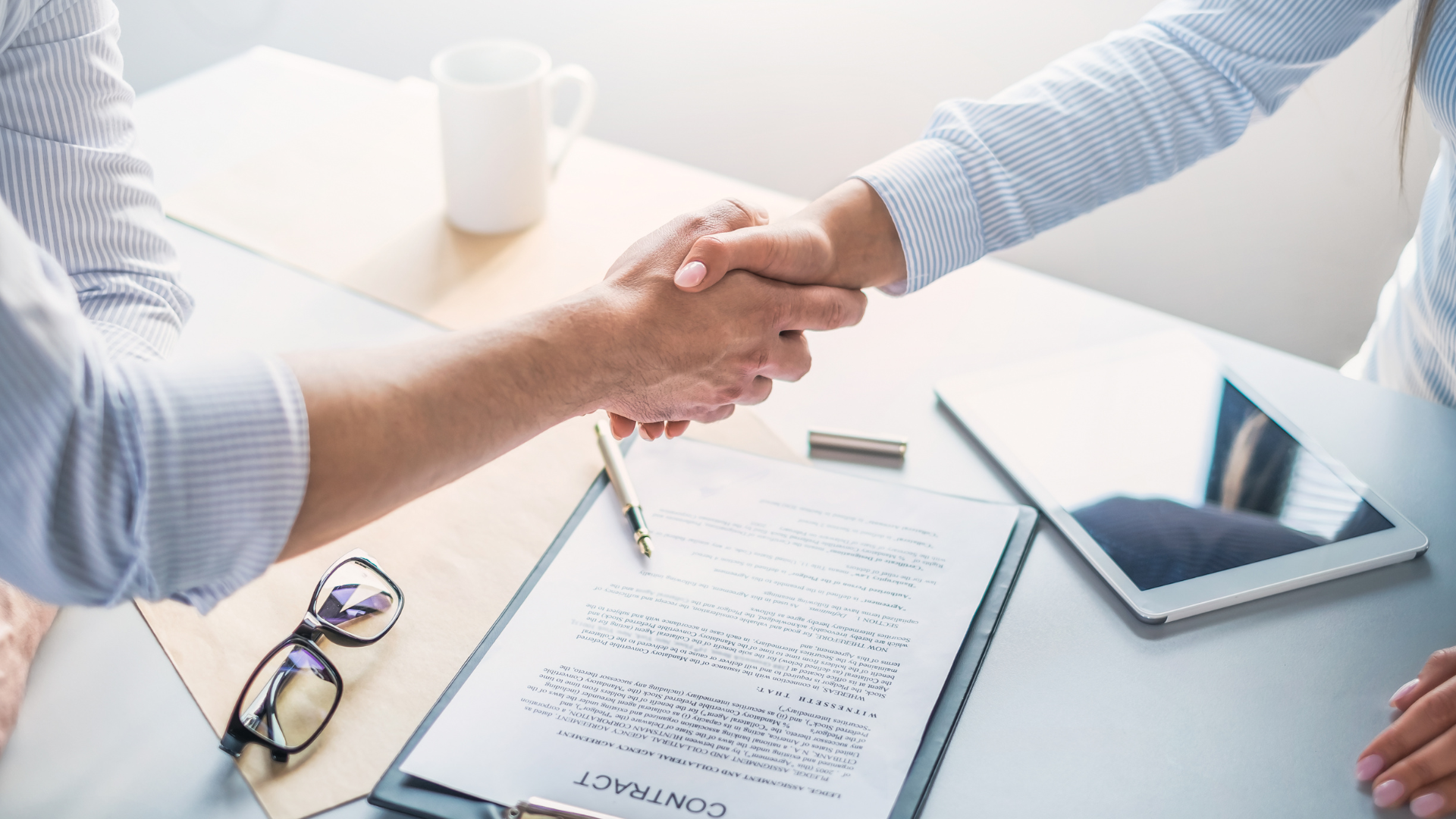 A man and a woman are shaking hands over a contract.