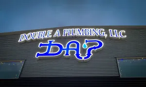 Double A Plumbing, LLC sign with blue logo on a dark building facade