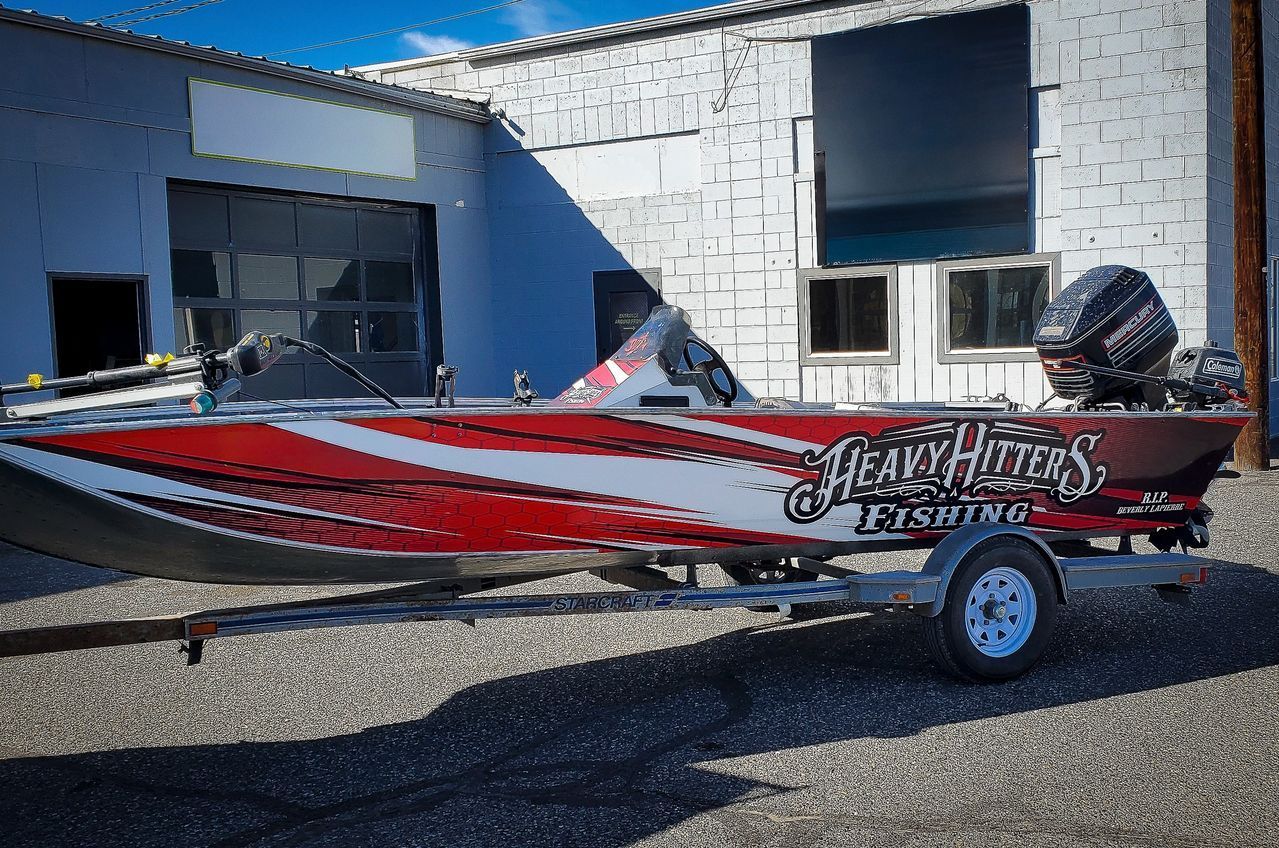 Red and white fishing boat on a trailer parked outside a building