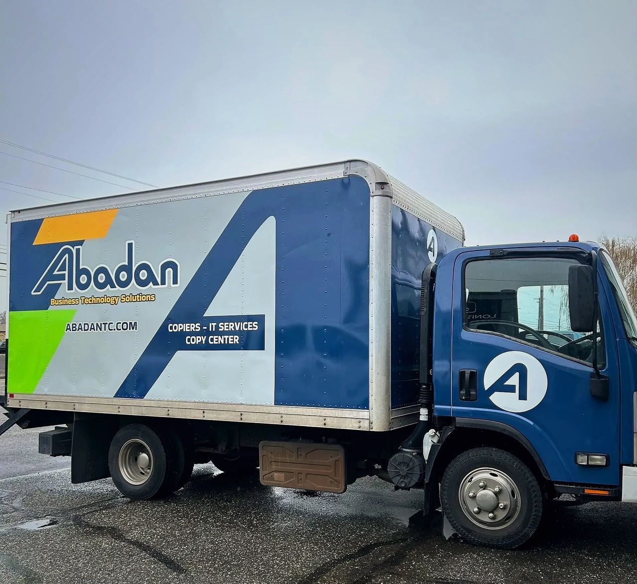 Blue Abadan box truck parked on a snowy roadside under an overcast sky