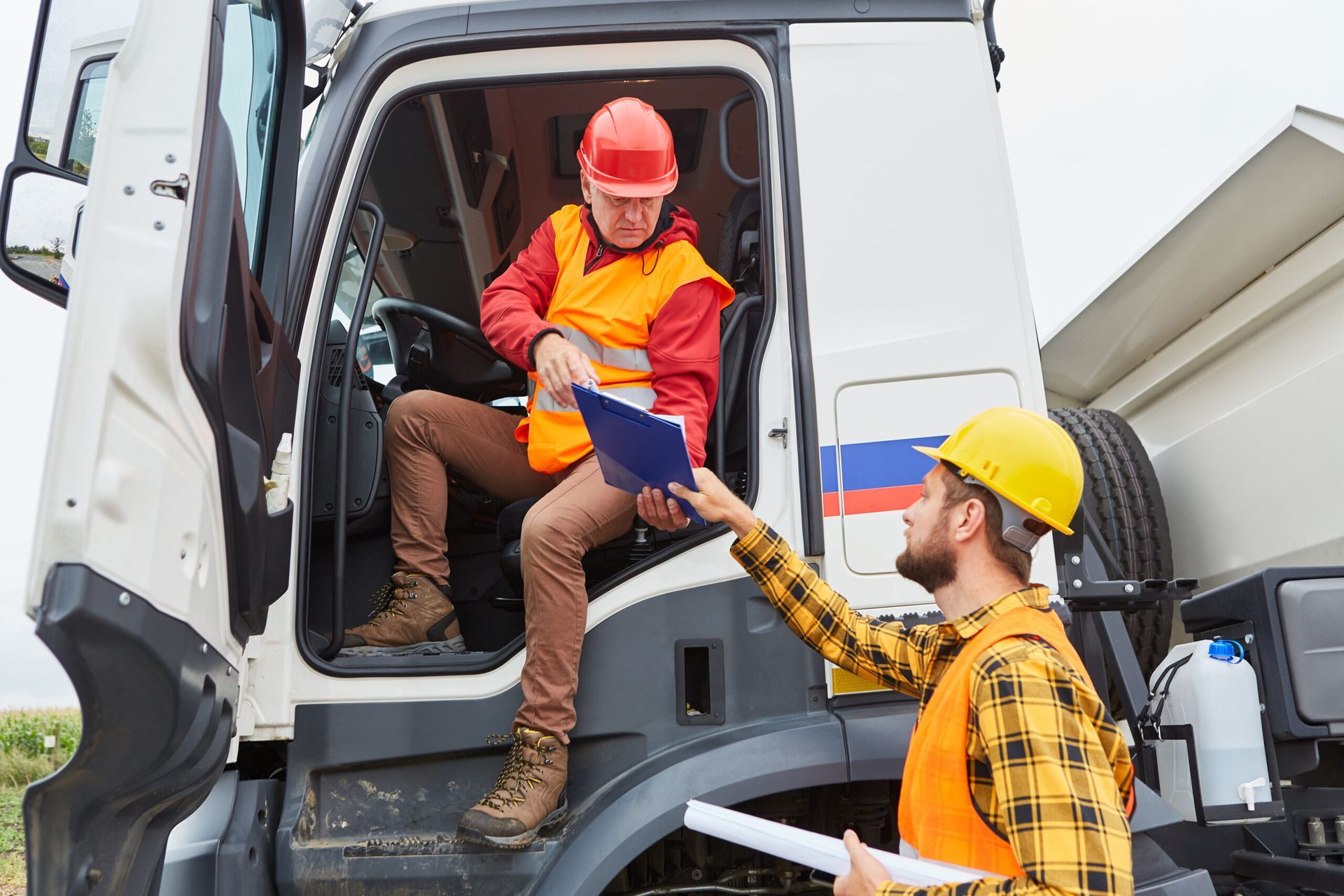Woman in yellow safety vest reviews paperwork next to colorful shipping containers.