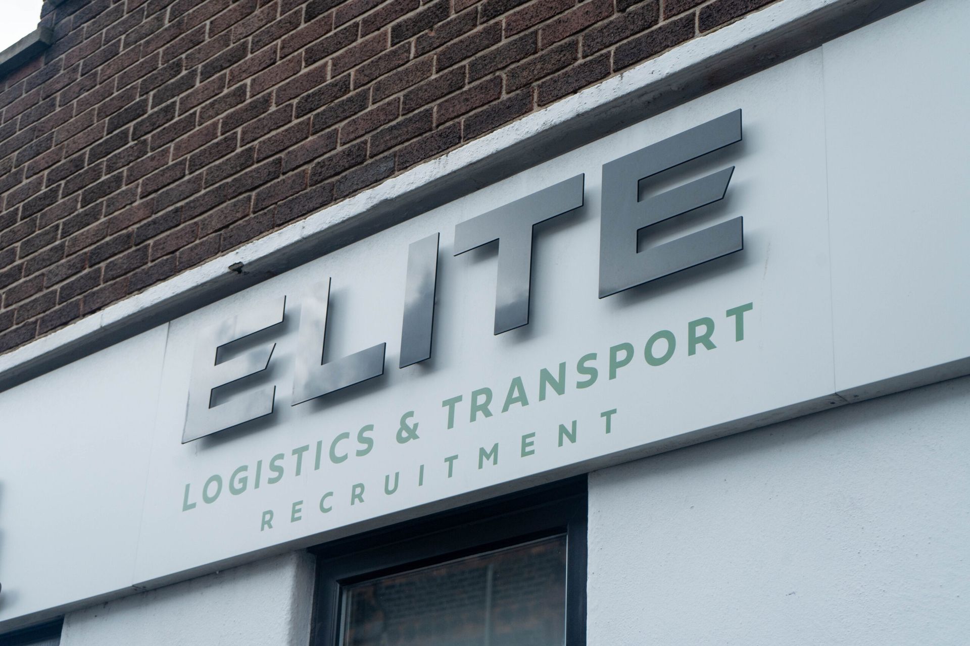 ELITE Logistics & Transport Recruitment sign on a white storefront against a brick building