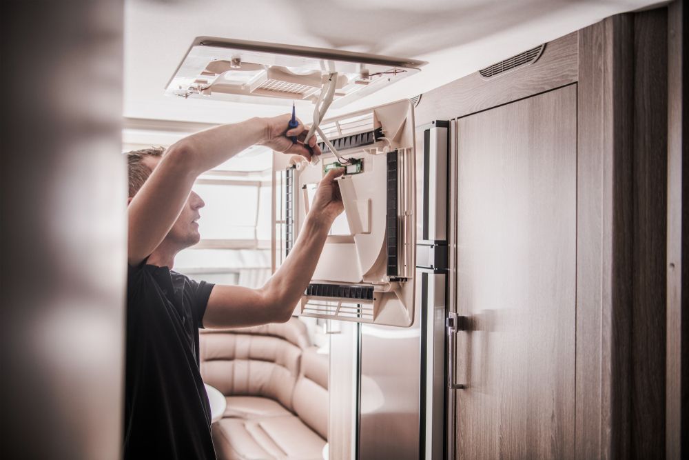 A man is working on a refrigerator in a camper — BA Auto Electrical In West Mackay, QLD