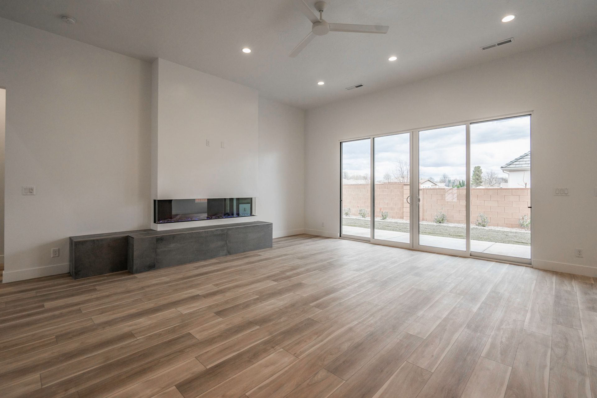 An empty living room with hardwood floors and sliding glass doors.