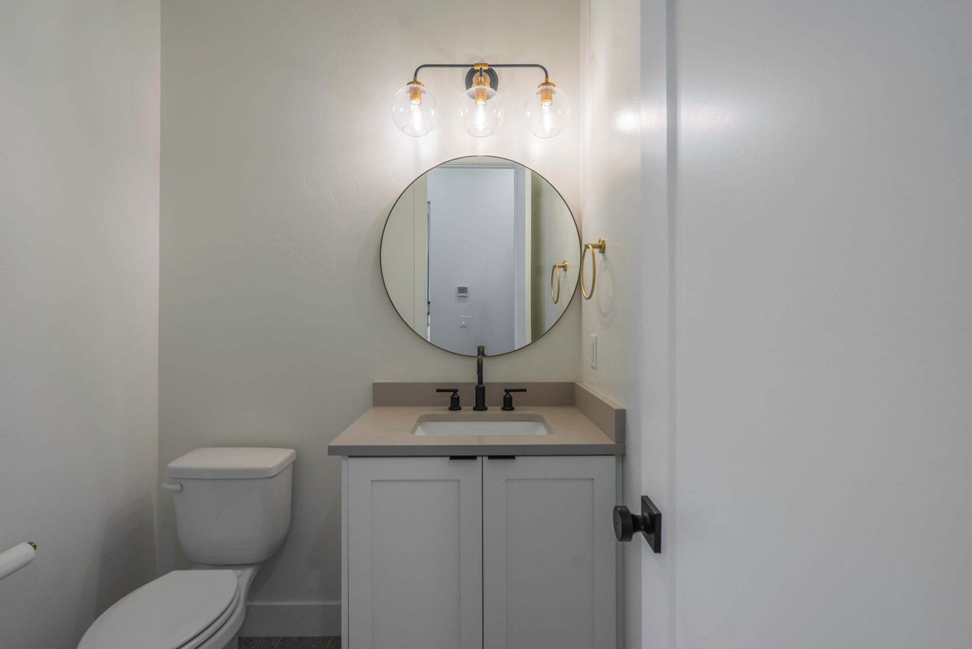 A bathroom with a toilet , sink and mirror.