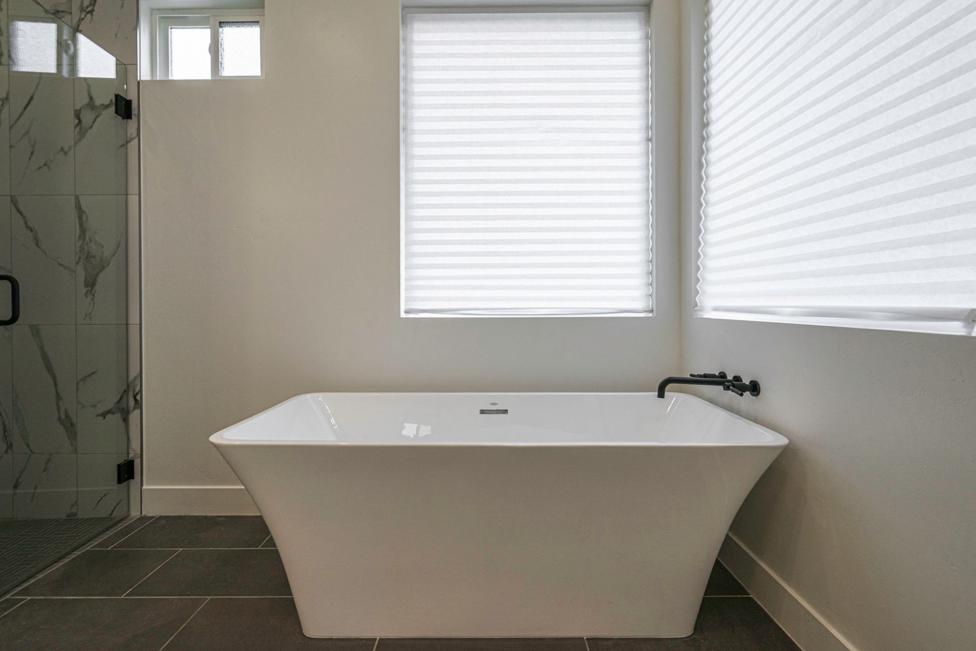 There is a bathtub in the bathroom next to a window.