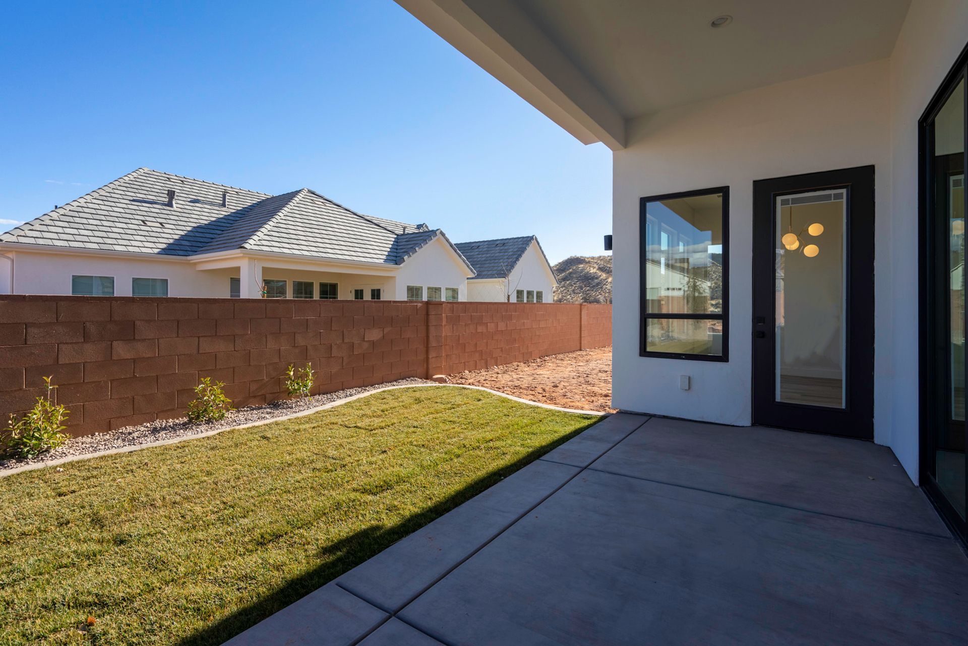 The backyard of a house with a patio and a brick wall.