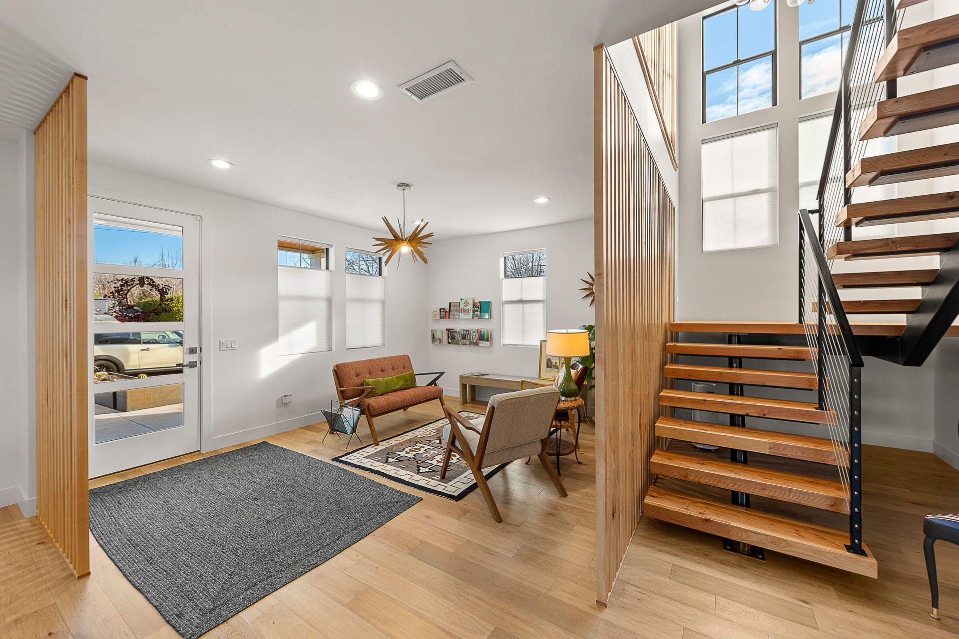 A living room with a wooden staircase leading to the second floor.