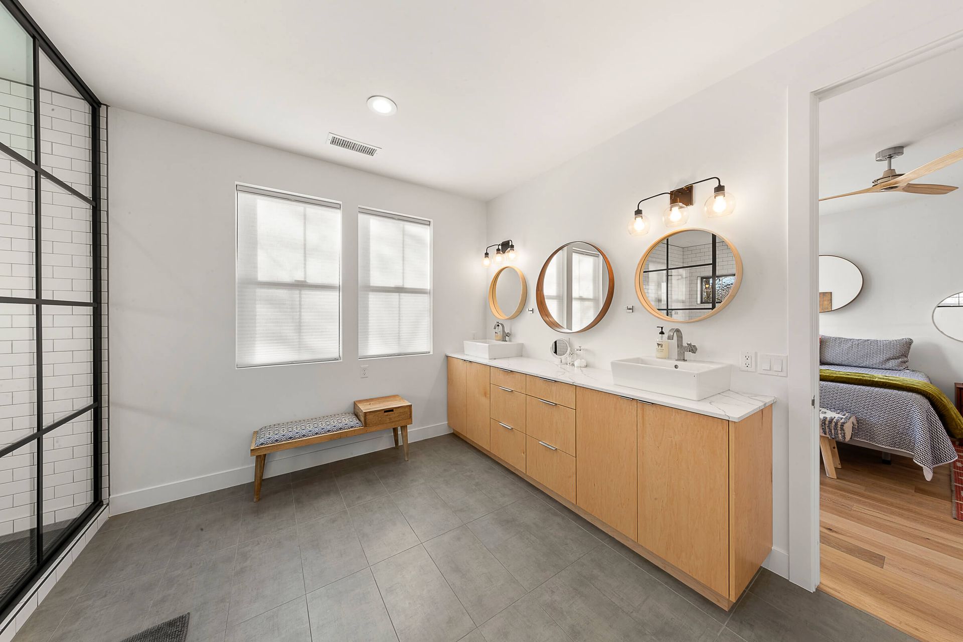A bathroom with two sinks , two mirrors and a bench.