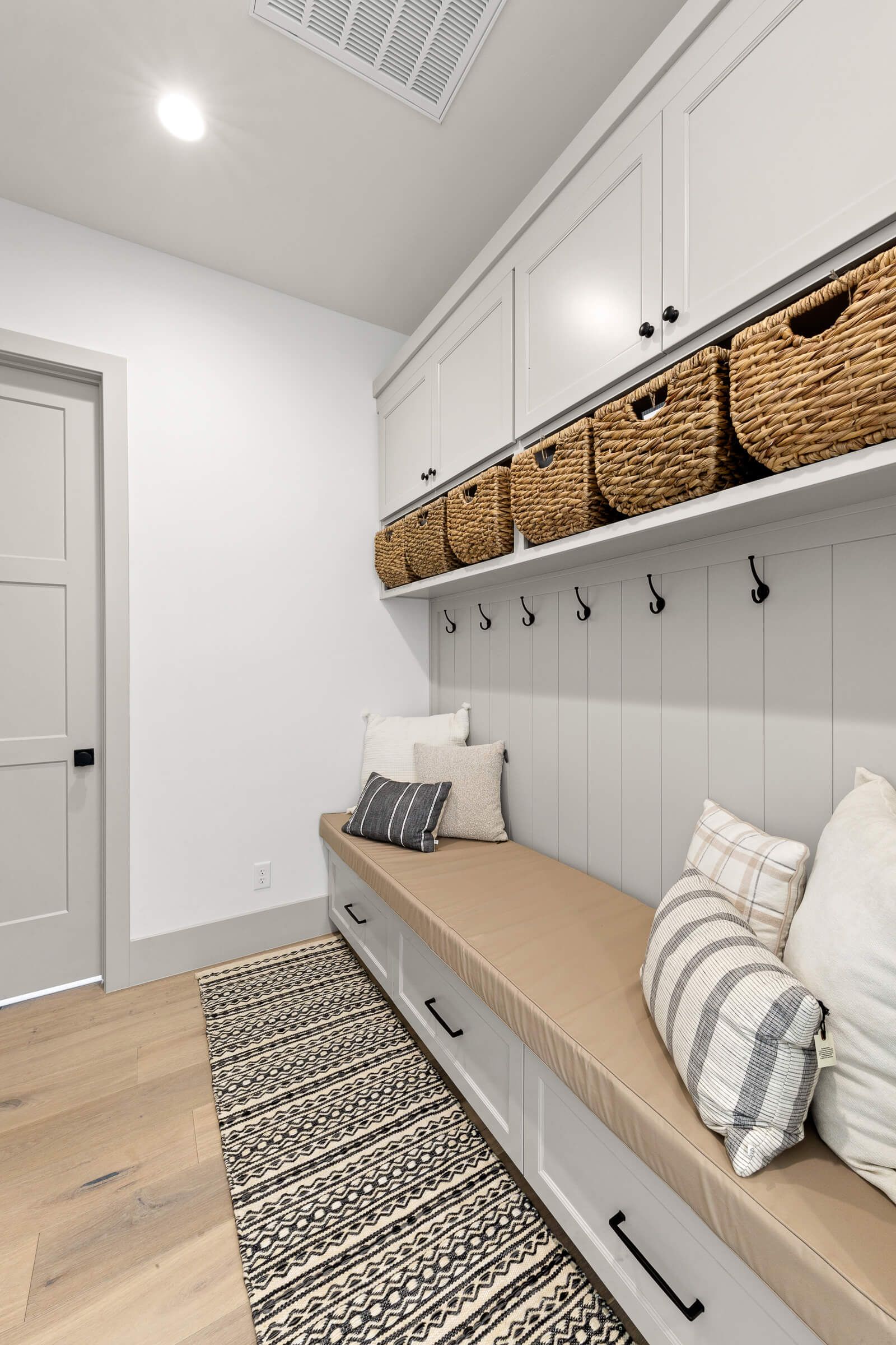 A mud room with a bench and baskets on the wall.