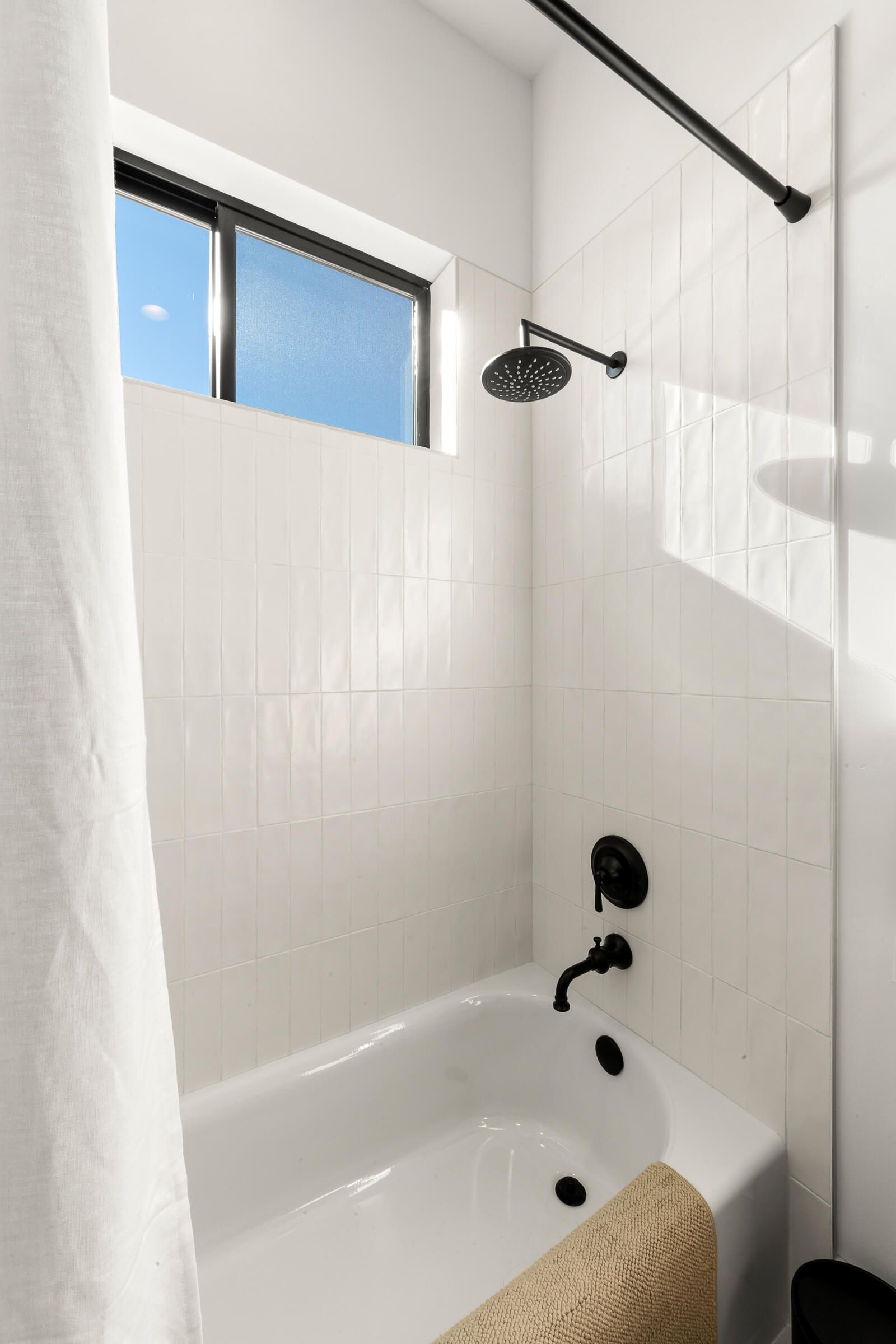 A bathroom with a bathtub , shower , and window.