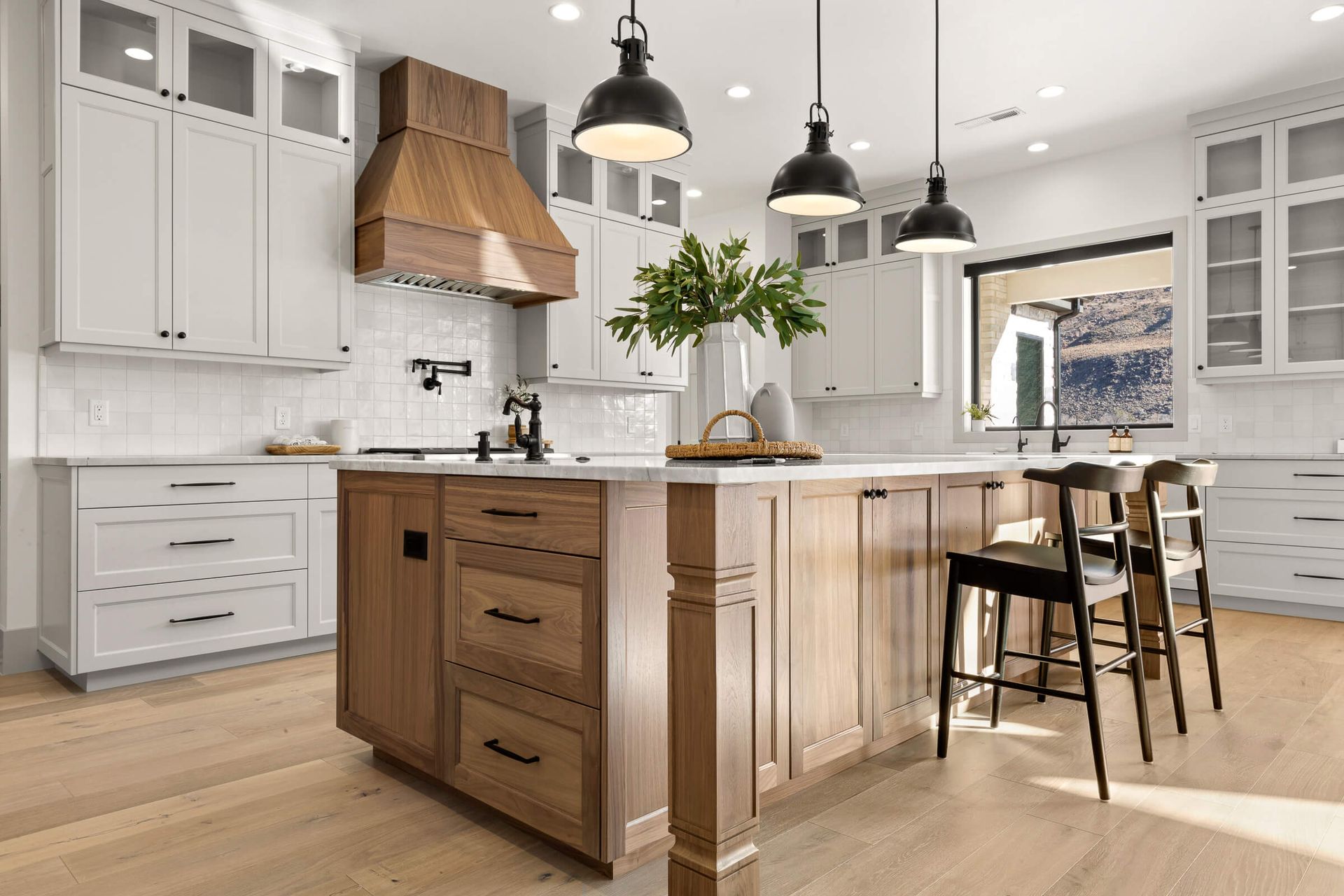 A kitchen with white cabinets and wooden cabinets and a large island.