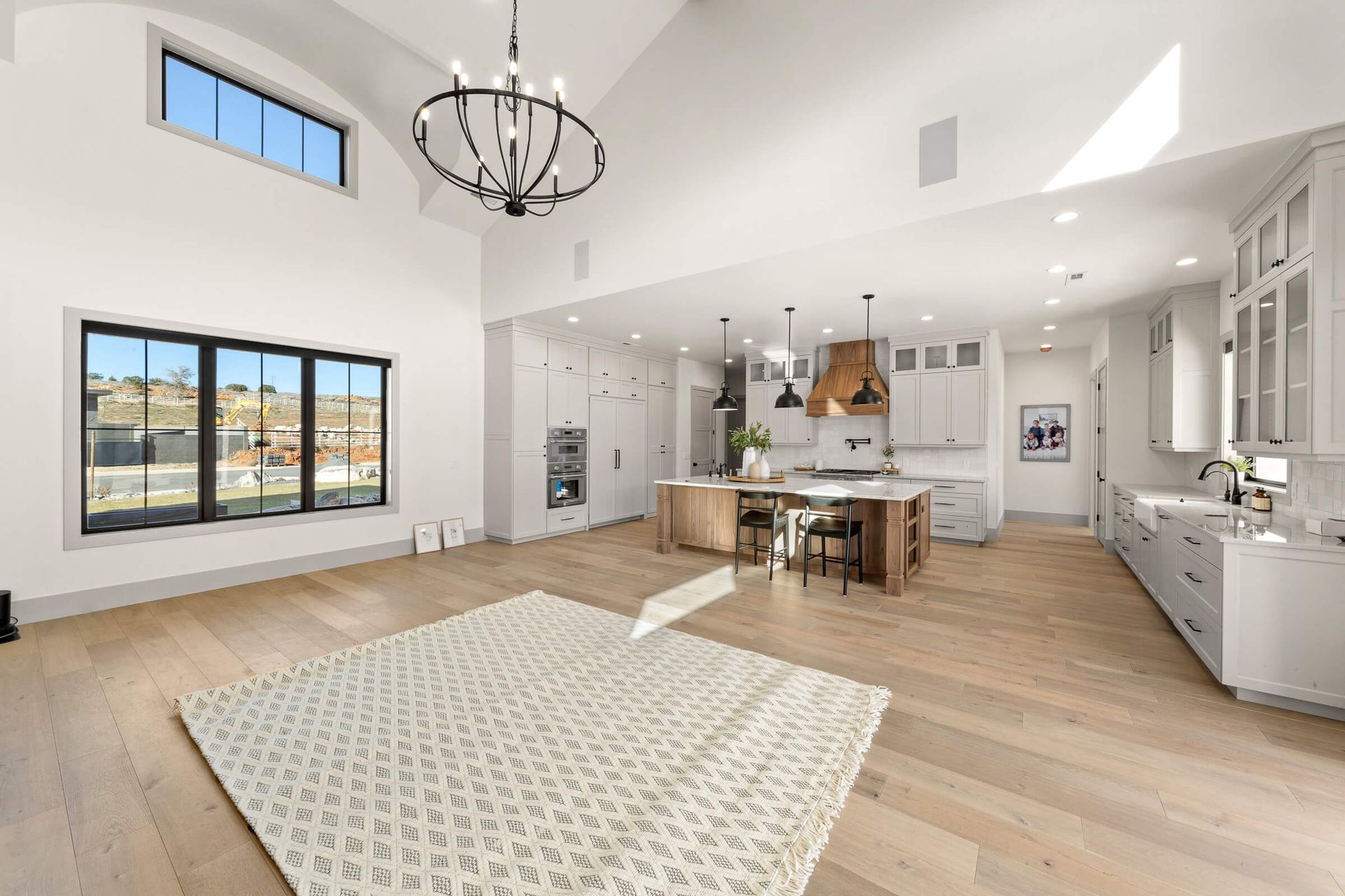 A living room with a rug and a kitchen in the background.