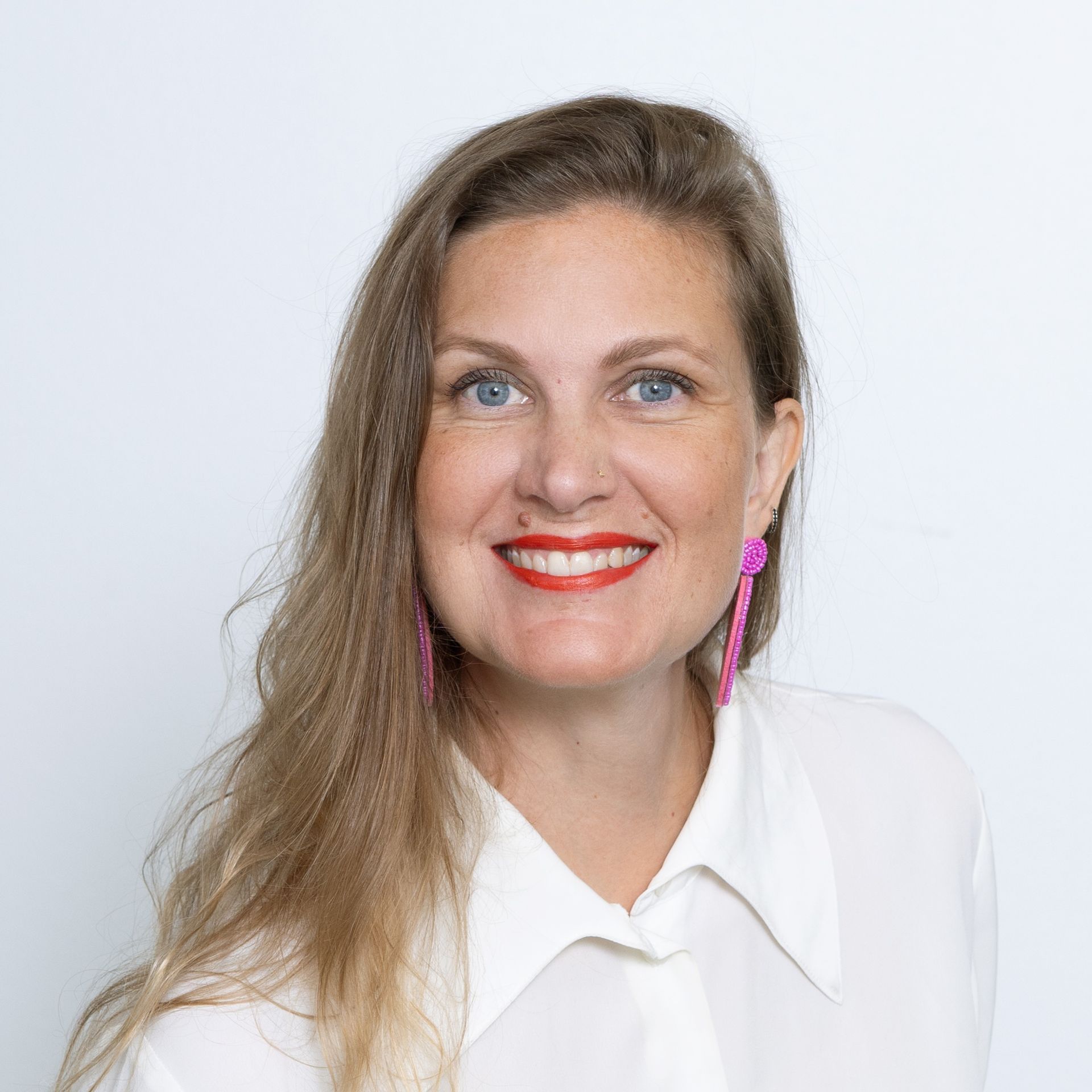 A woman wearing glasses and a white shirt is smiling