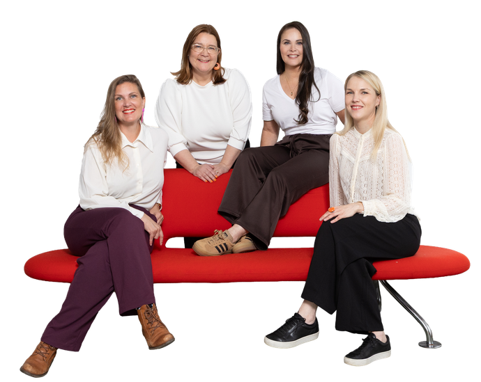 A group of women are sitting on a red couch talking to each other.