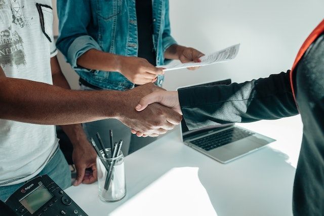 two people shaking hands as someone else reviews a document