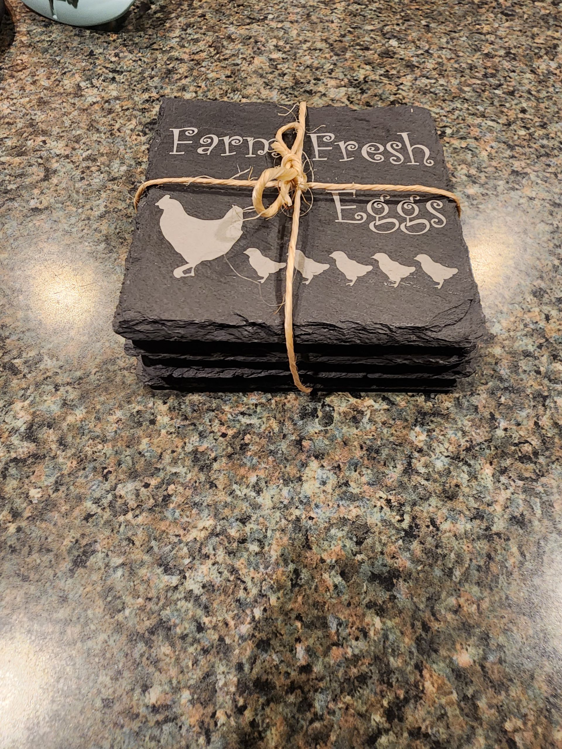 Stack of black paper coasters tied with twine on a speckled countertop, labeled 