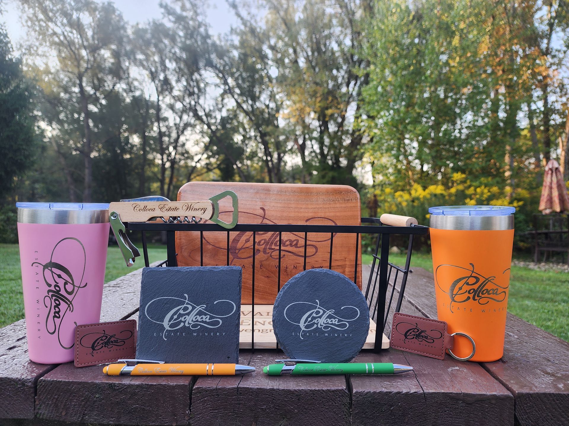 Pink and orange tumblers with notebooks and pens arranged on an outdoor table.