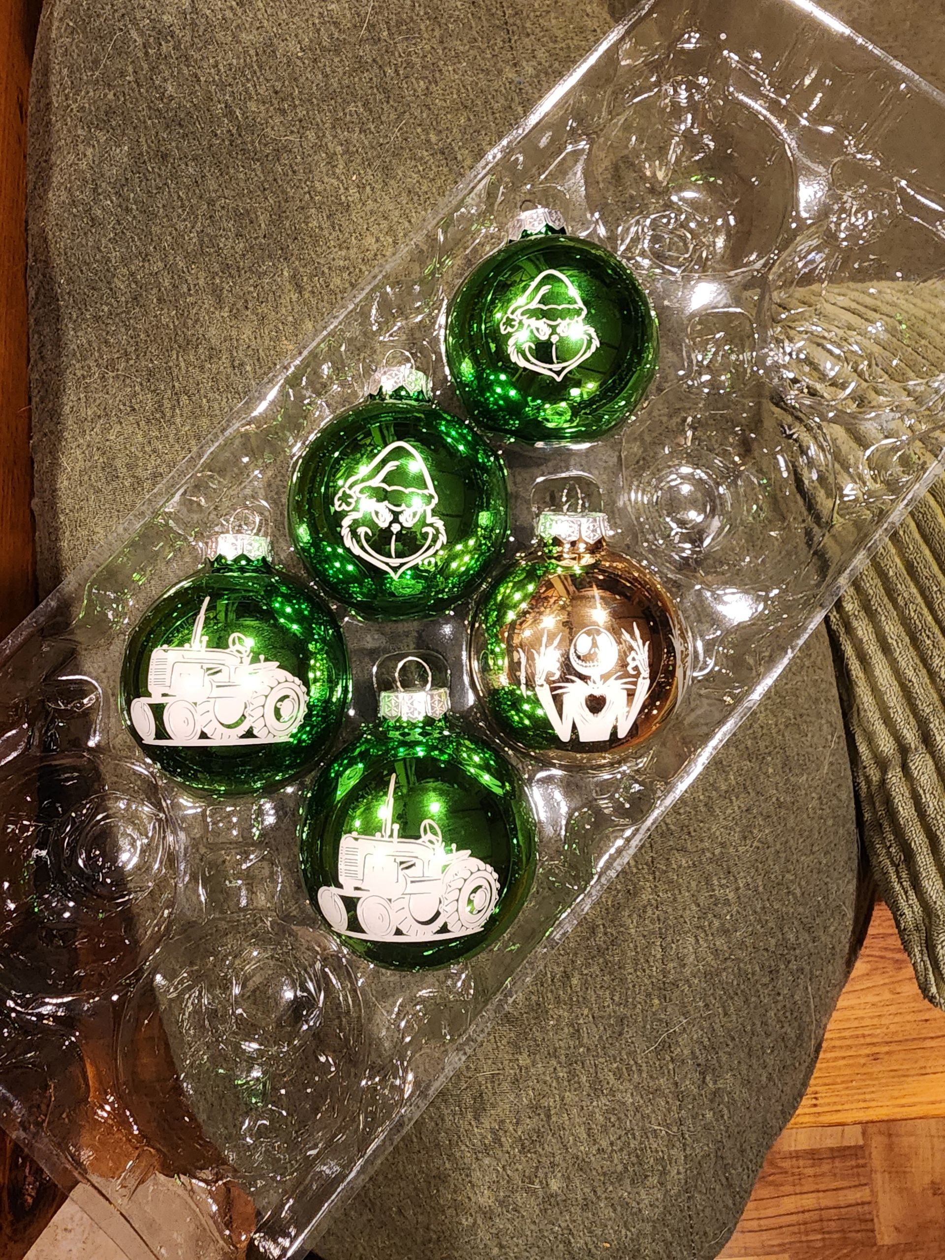 Five green-and-white holiday ornaments in a clear plastic bag on a textured surface
