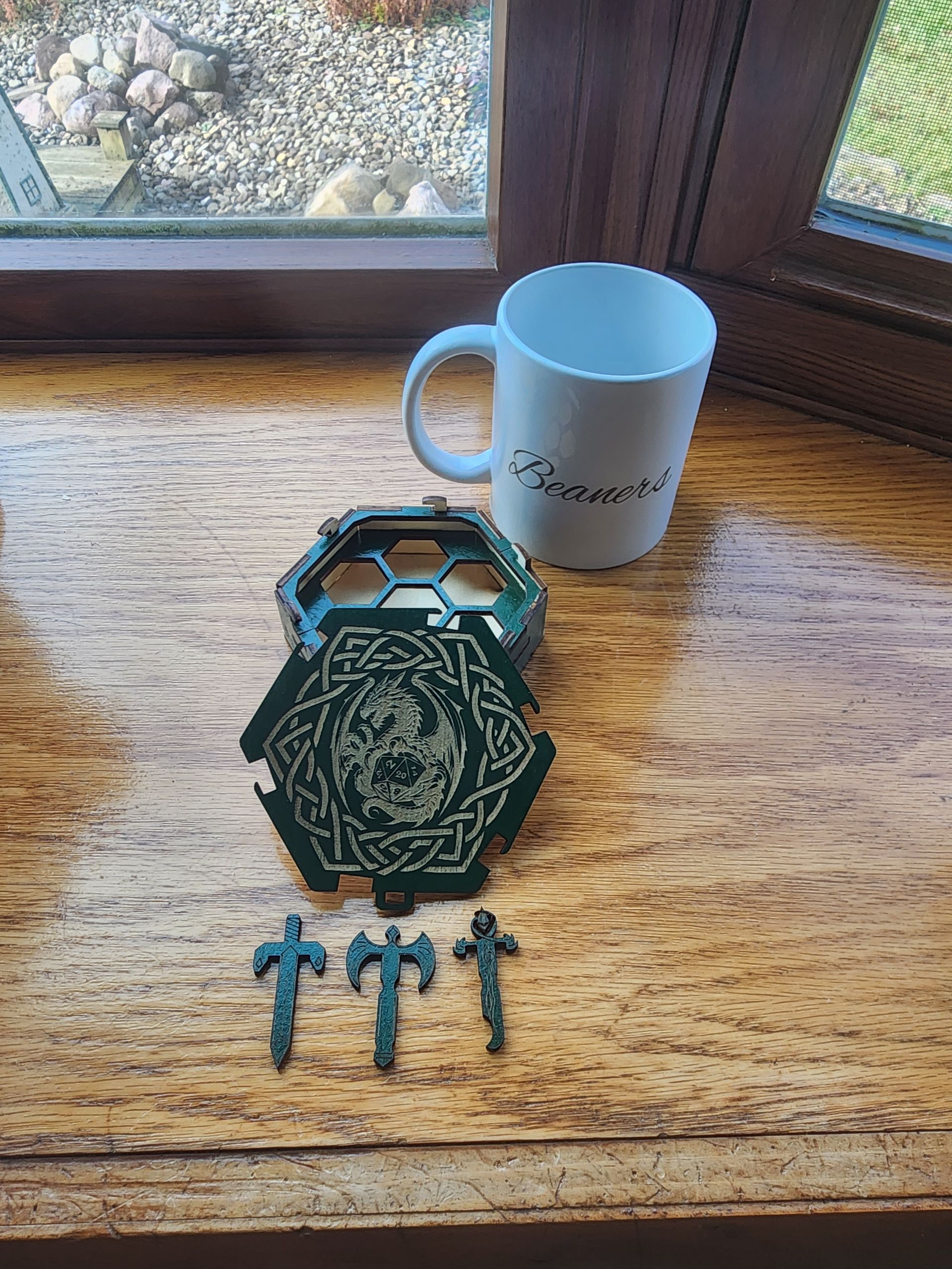 Turquoise keychain and four keys on a wooden table beside a white mug near a window