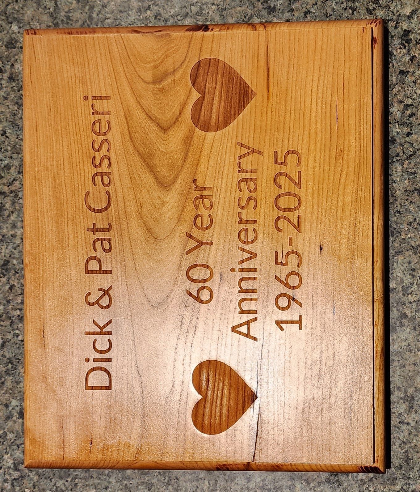 Wooden plaque reading “Dick & Pat Casseri 60 years Anniversary 1965–2025” with heart cutouts