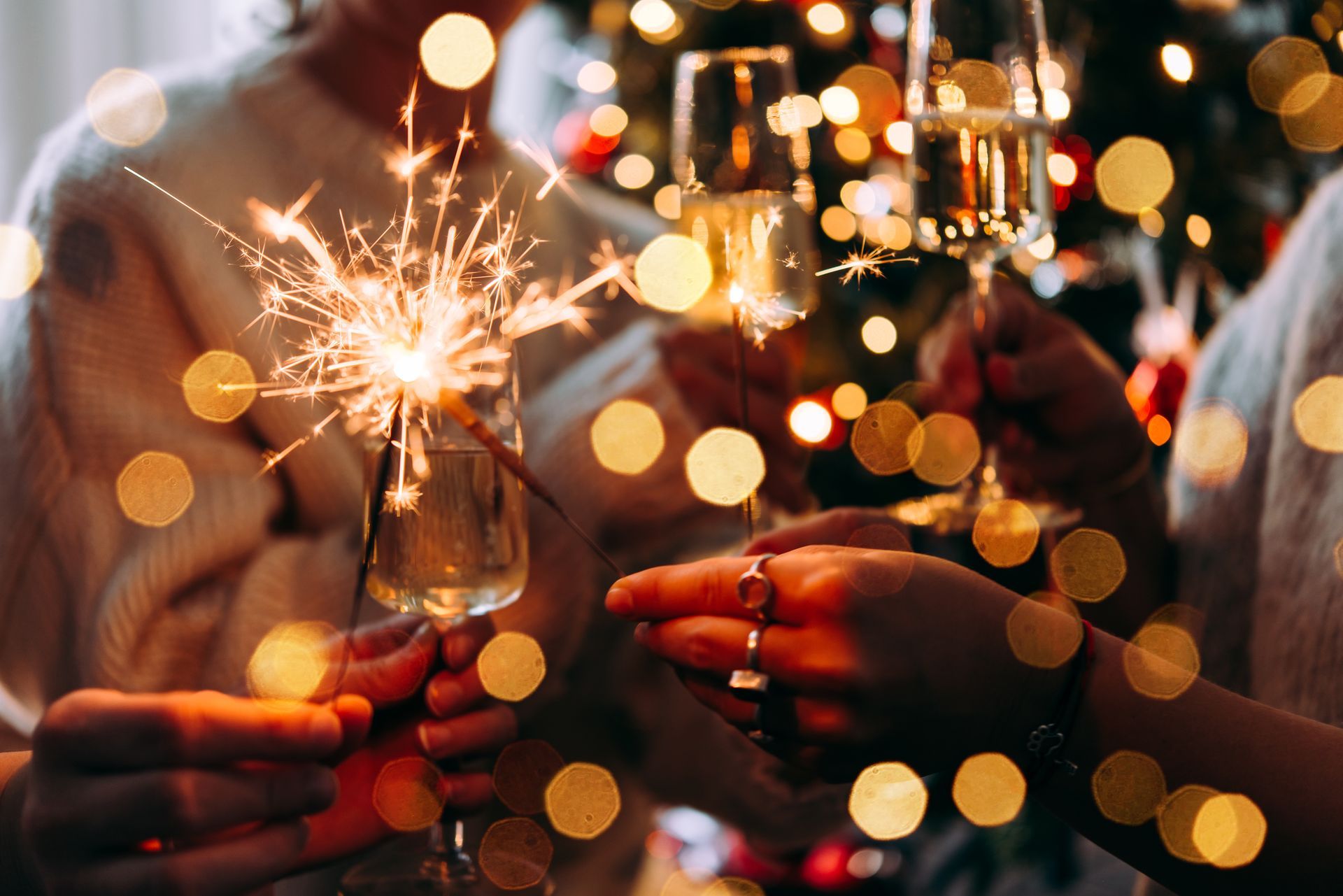 Menschen stoßen mit Champagner an und halten Wunderkerzen bei einer festlichen Weihnachtsfeier mit Lichtern.