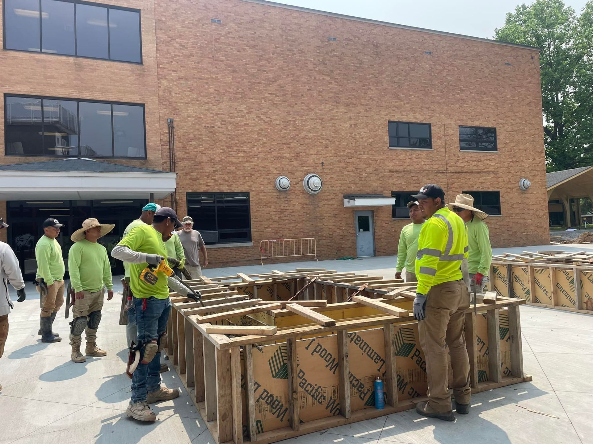 A group of construction workers are standing in front of a large brick building.