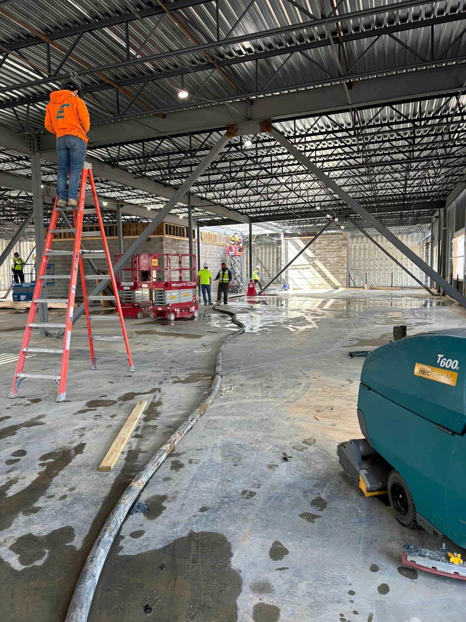 A man is standing on a ladder in a building under construction.