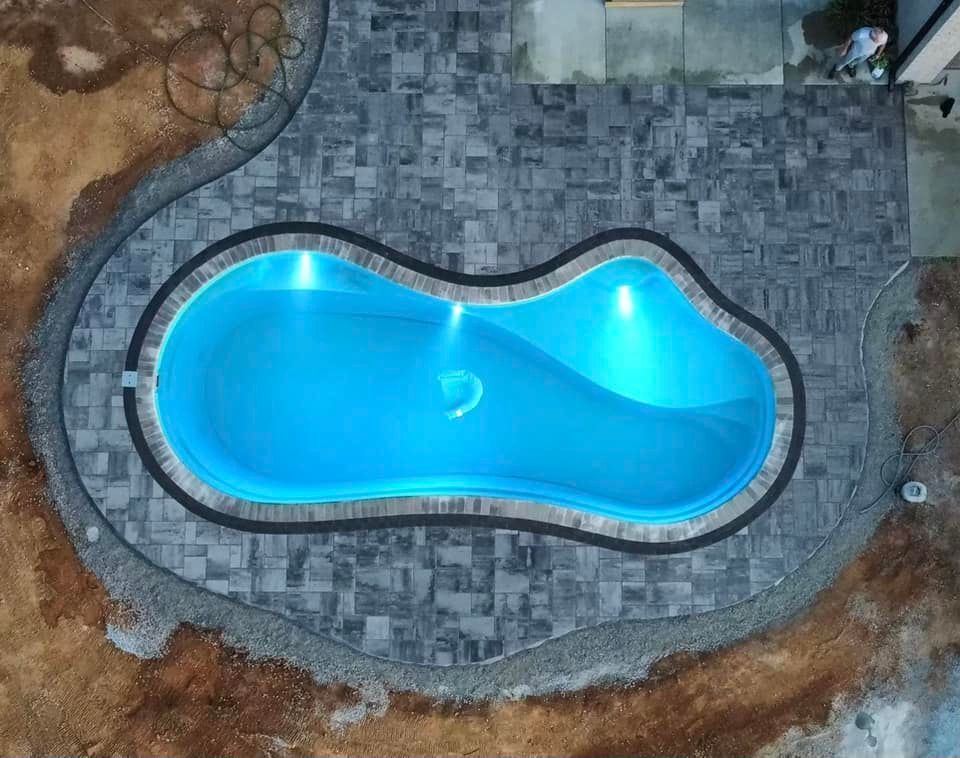 An aerial view of a swimming pool with lights on it.