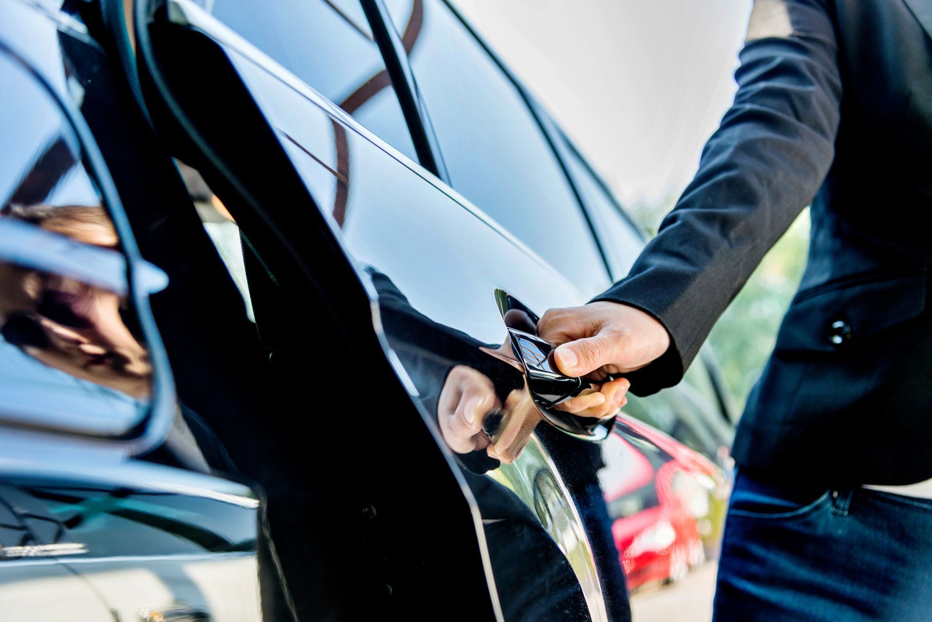 A man in a suit is opening the door of a car.