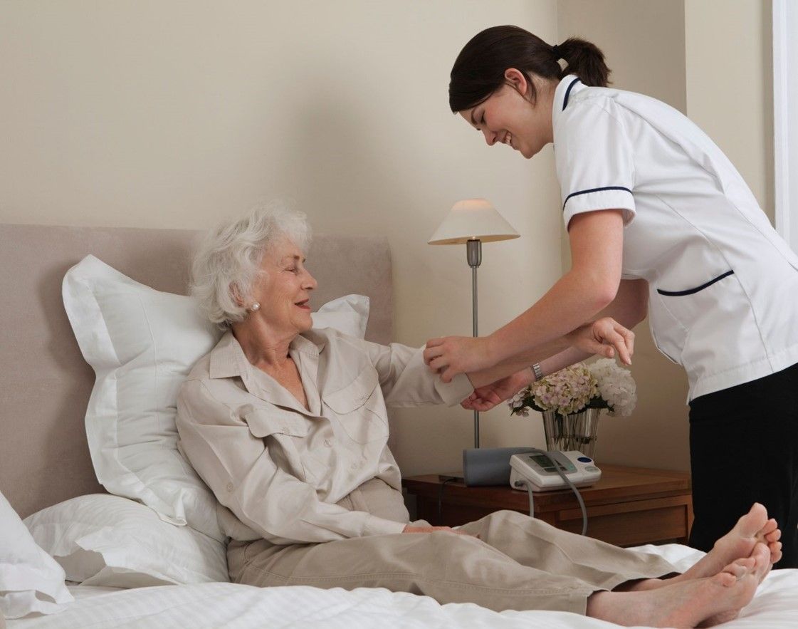 An in-home caregiver, wearing a blue uniform, hugging a senior. An in-home caregiver, wearing a blue uniform, hugging a senior.