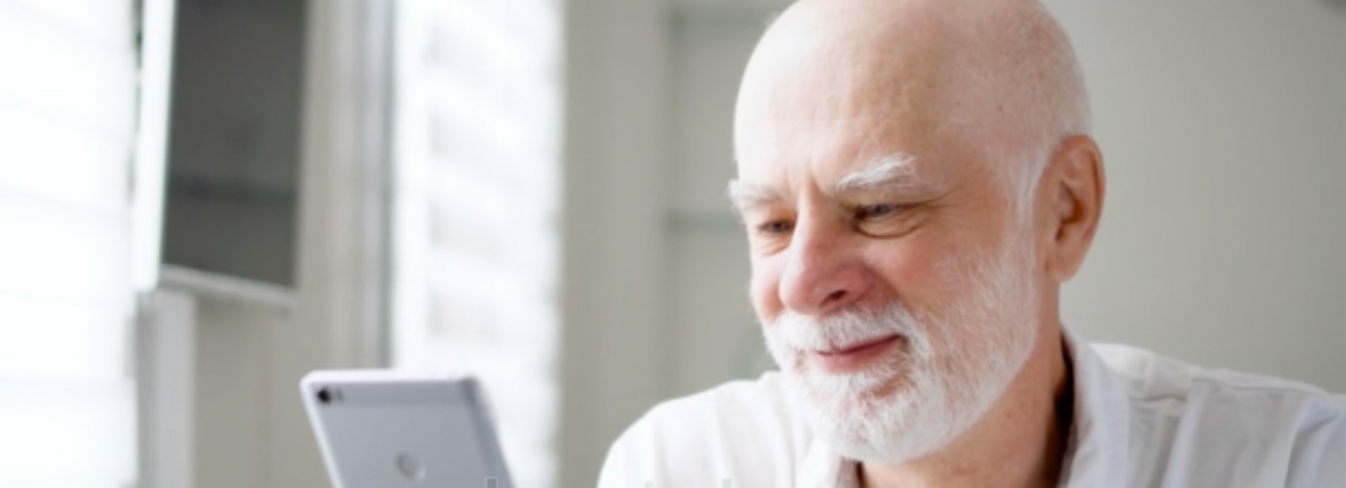 An older man with a beard is using a tablet computer.