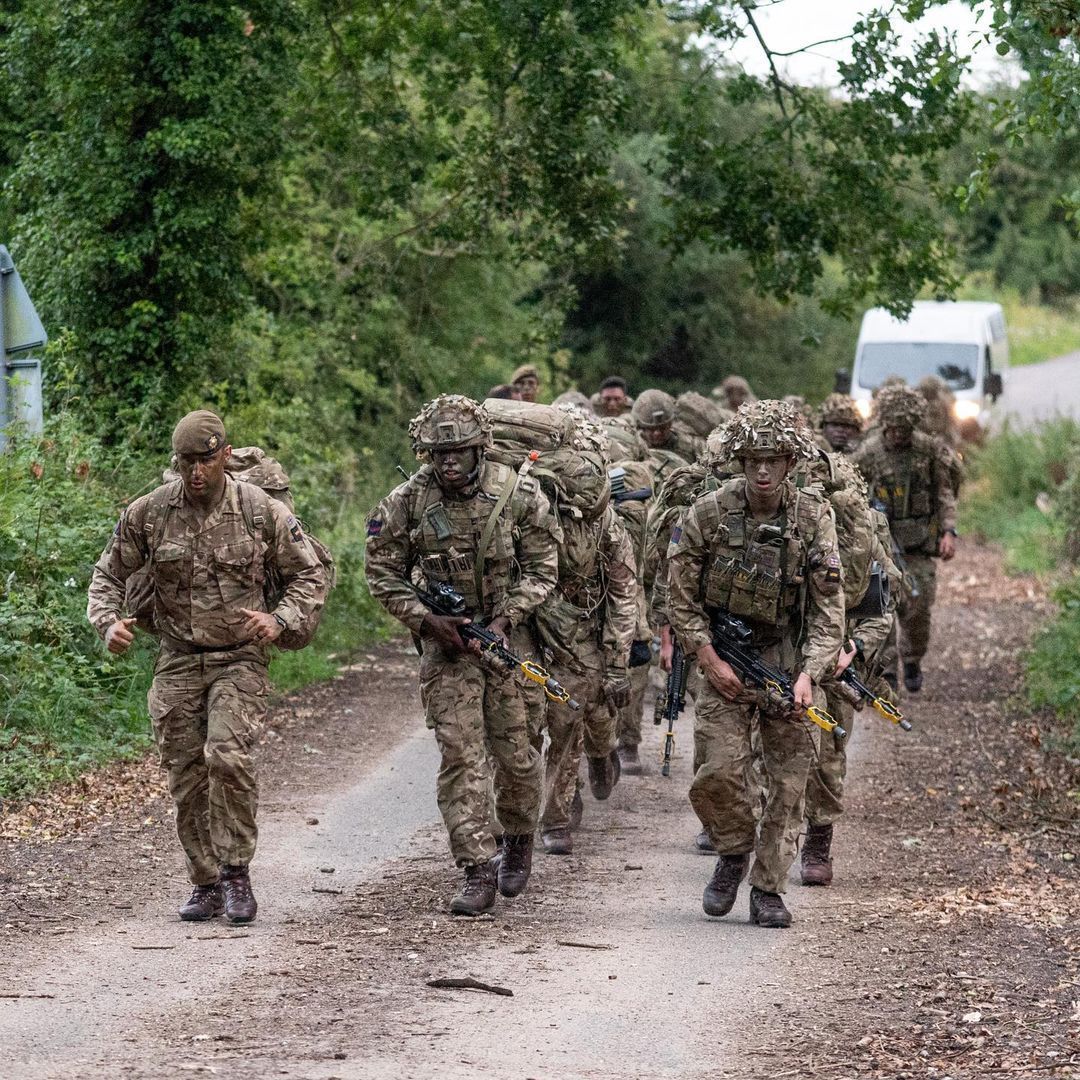 A group of soldiers are walking down a dirt road.
