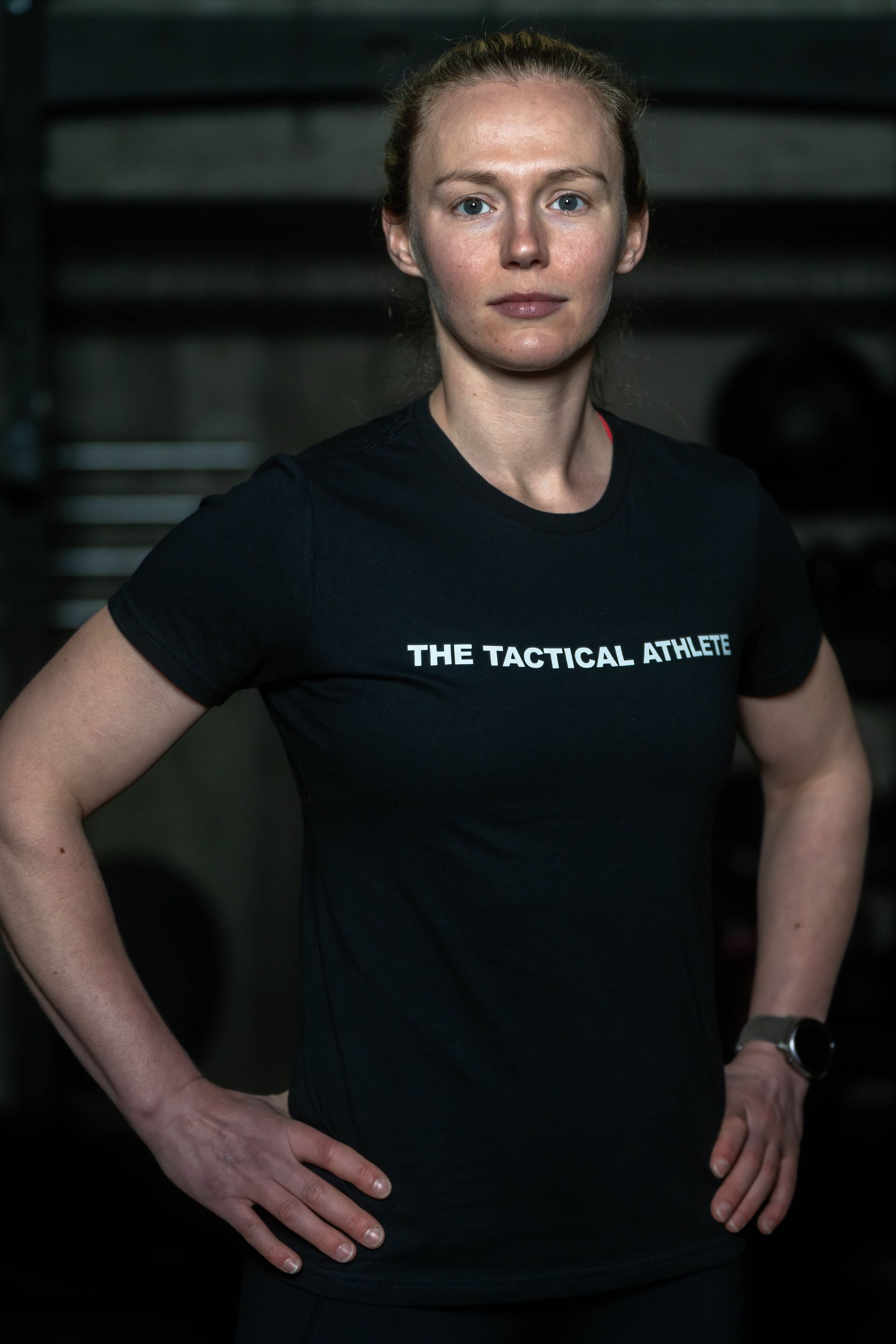 A woman is wearing a black t-shirt that says the tactical athlete.