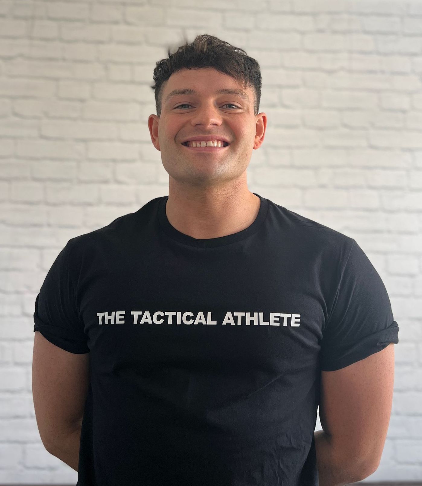 A man wearing a black t-shirt that says the tactical athlete